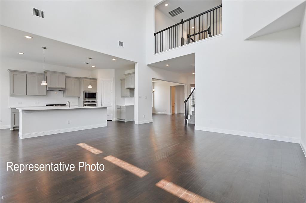 Open-concept living area with wood-finish flooring and a two-story ceiling