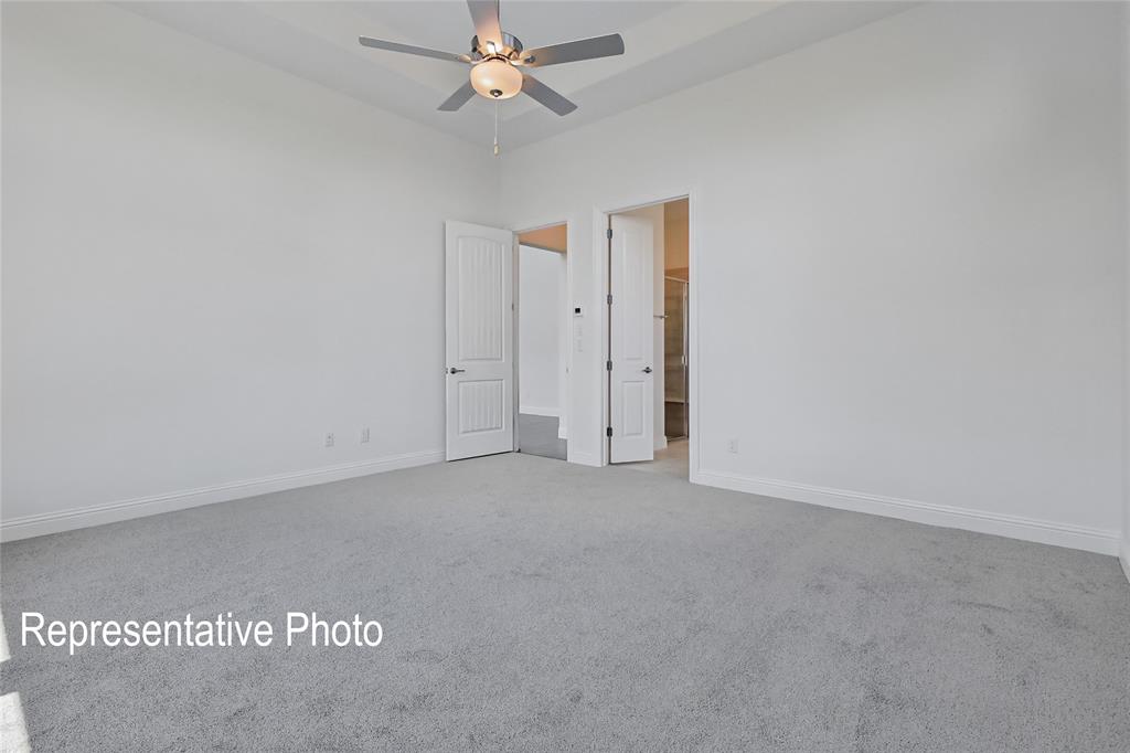 Spacious room with light gray carpeting, crisp white walls, a tray ceiling, and a ceiling fan with integrated lighting