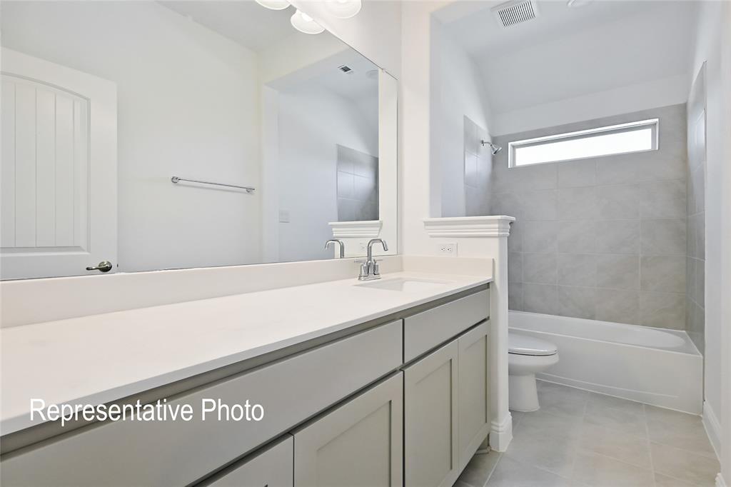 Bathroom featuring a spacious vanity with an undermount sink, a large mirror, contemporary cabinetry, and a full-size bathtub with a tiled surround