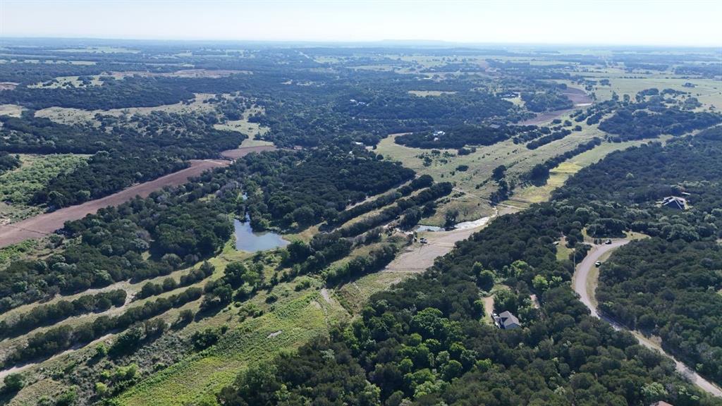 Expansive aerial landscape featuring a large body of water, extensive tree coverage, and several clearings