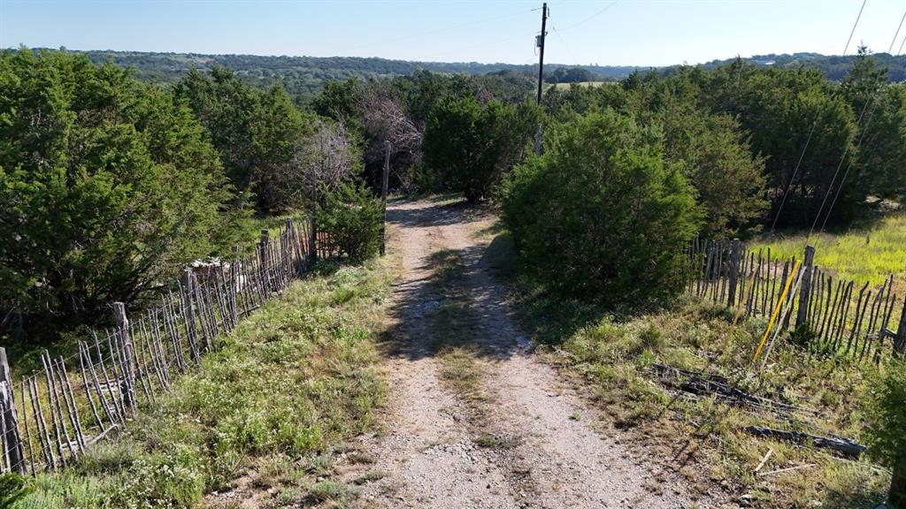 Unpaved drive bordered by rustic wooden fencing and abundant natural foliage