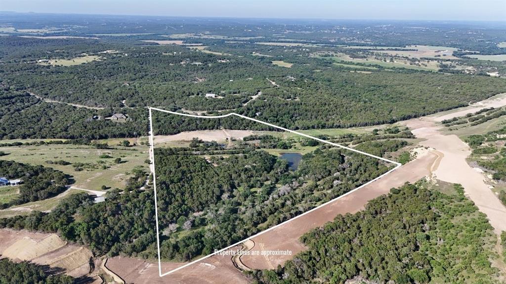 Expansive land parcel featuring dense tree coverage, open fields, and a visible pond