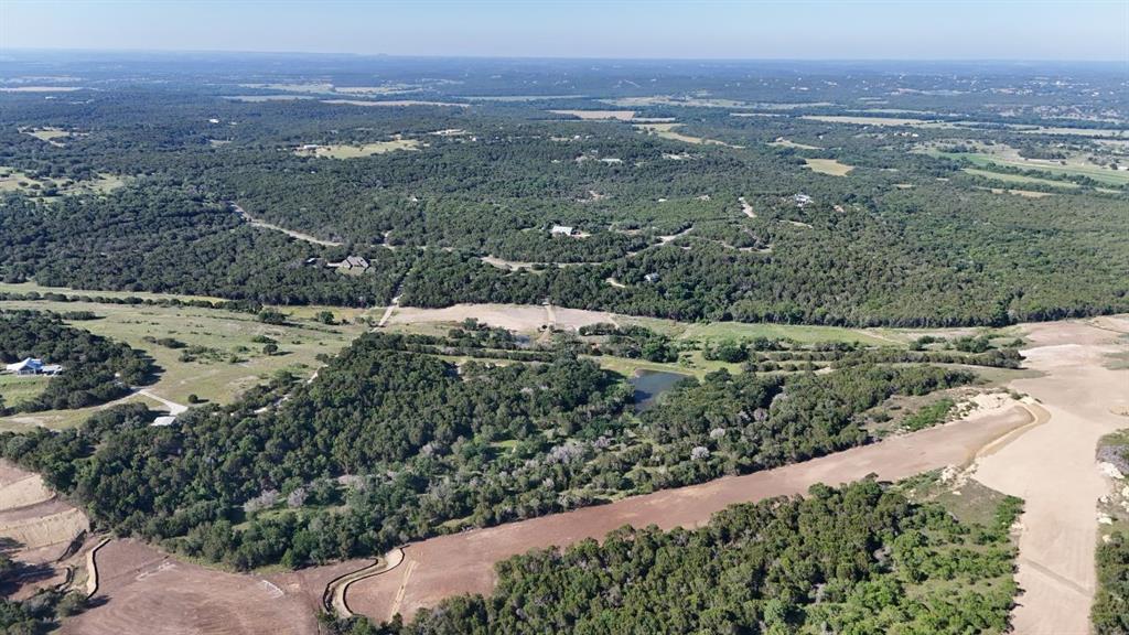 Expansive aerial view showcasing diverse terrain including wooded areas, open fields, and a natural pond