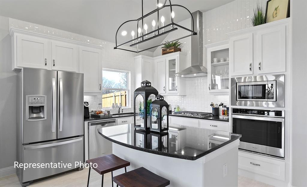 Kitchen featuring white cabinetry, stainless steel appliances, a center island with a dark countertop, a tile backsplash, and an overhead light fixture