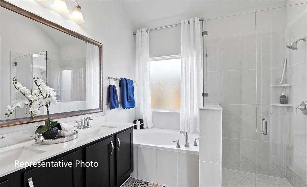 Bathroom featuring a double vanity with dark cabinetry, integrated dual sinks, and a large framed mirror