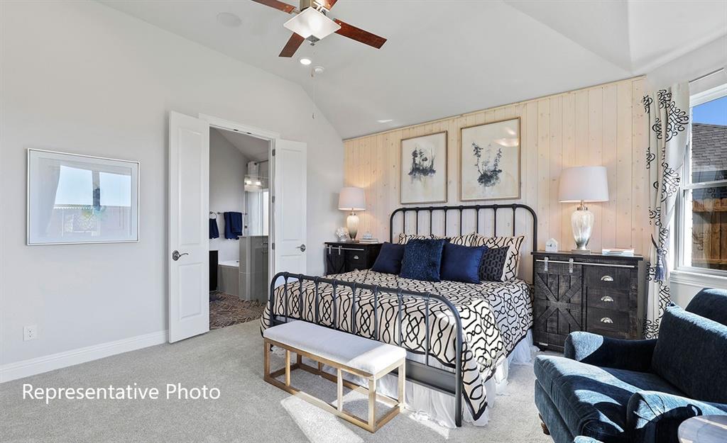 Vaulted ceiling bedroom featuring carpet flooring, shiplap accent wall, ceiling fan, and double doors opening to a bathroom
