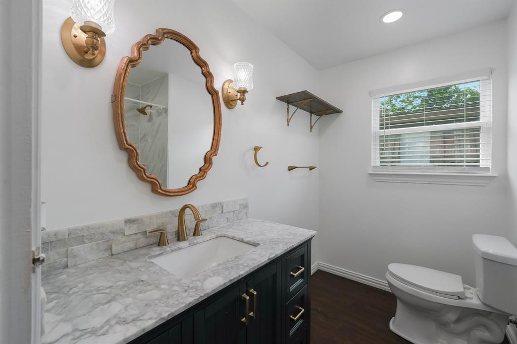 Bathroom featuring a vanity with a light-toned countertop, a decorative mirror, and wall-mounted sconces.