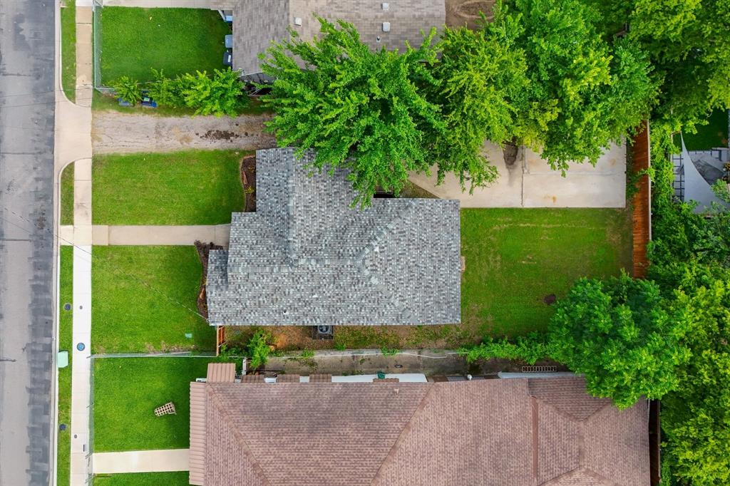 Aerial perspective showcasing a property with a gray shingle roof, a front lawn, and a concrete driveway