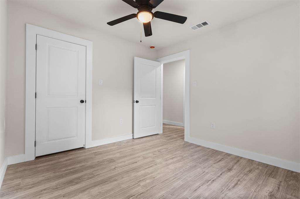 Interior room featuring wood-finish flooring, light neutral wall paint, white trim, and a ceiling fan with integrated lighting