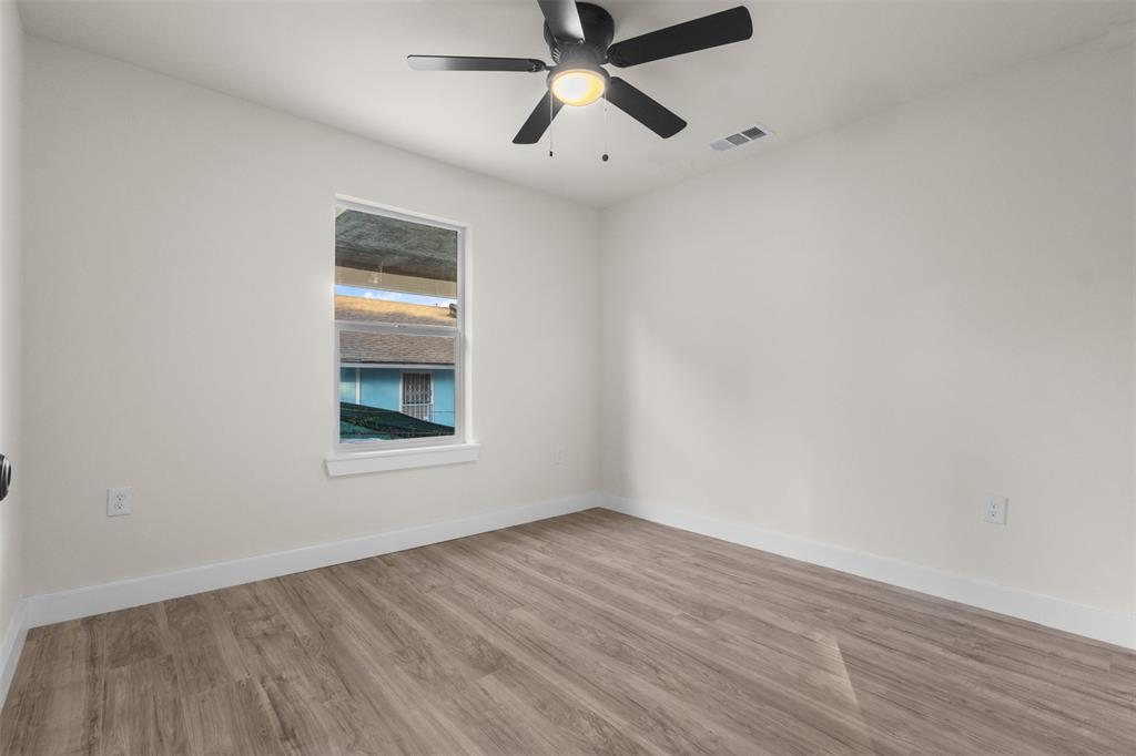 Bright room featuring wood-finish flooring, white baseboards, a single window with white trim, and a ceiling fan with integrated lighting