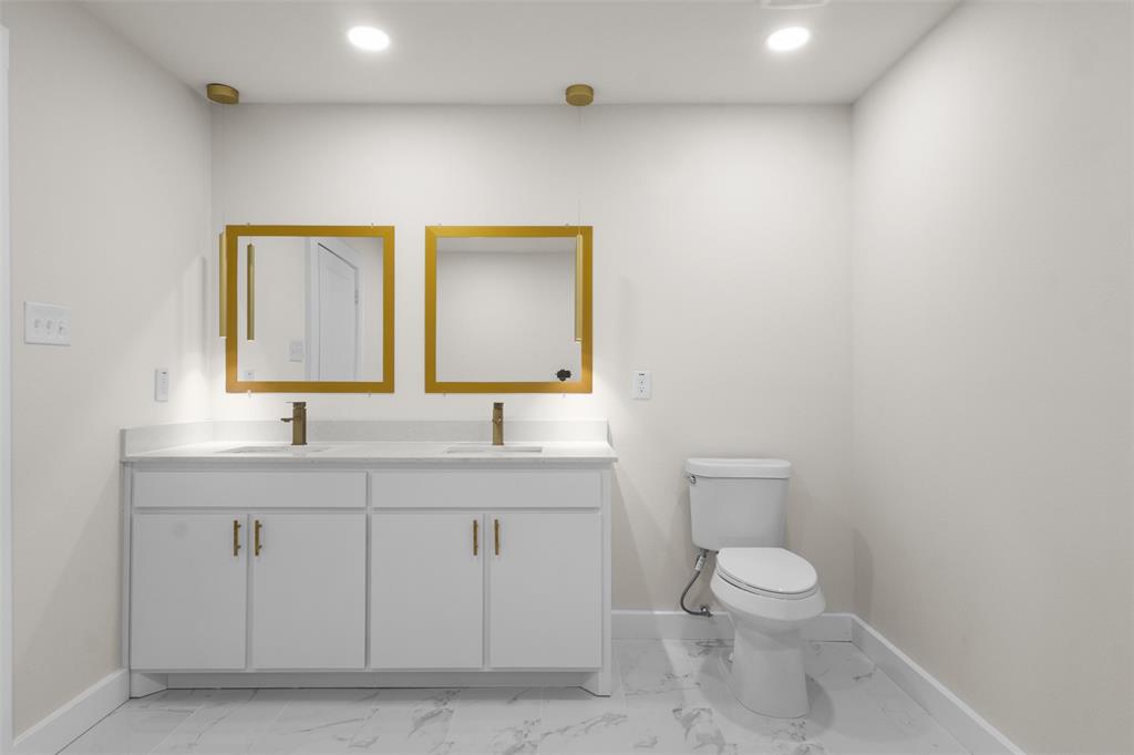 Dual vanity with white cabinetry, gold-toned hardware, and rectangular under-mount sinks