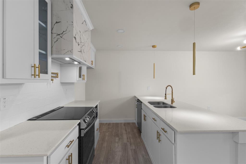 Contemporary kitchen featuring white cabinetry with gold-tone hardware, a white subway tile backsplash, and light-toned countertops