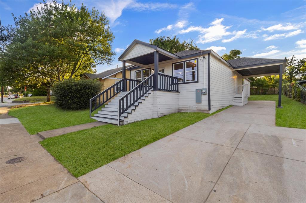 Ranch-style residence featuring white siding, a covered front porch with black railings, a paved driveway, and a covered carport Ranch-style residence featuring white siding, a covered front porch with black railings, a paved driveway, and a covered carport