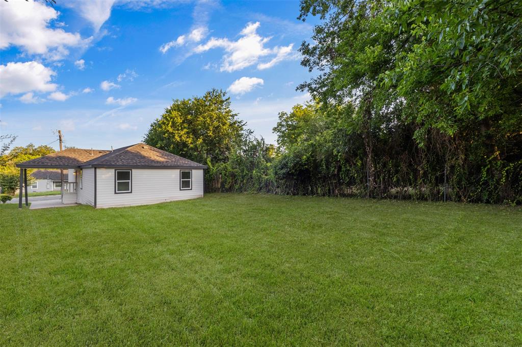 Expansive rear yard featuring a large grass area and mature perimeter foliage