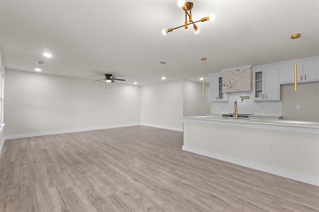 Expansive open-concept space featuring wood-finish flooring, recessed lighting, and a contemporary ceiling fan