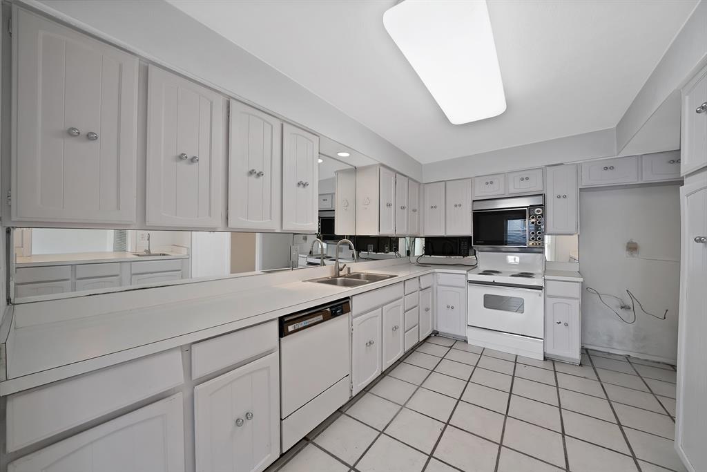 Kitchen featuring white cabinetry, integrated appliances, mirrored backsplash, laminate countertops, and tile flooring