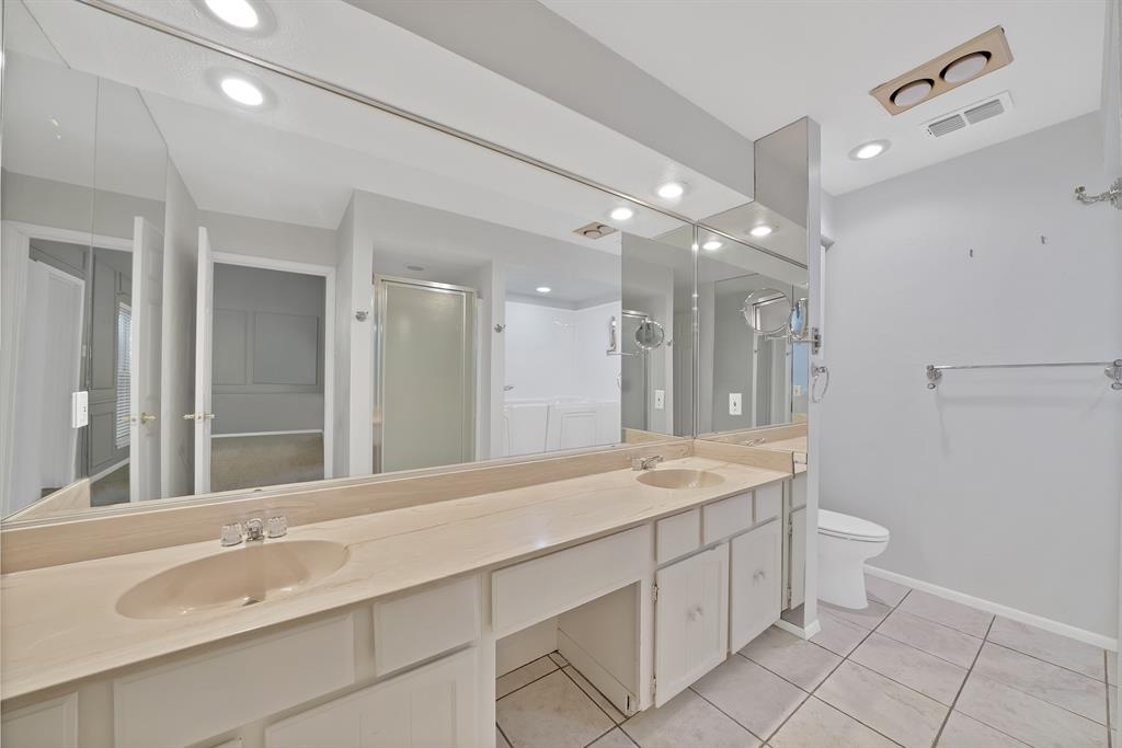 Bathroom featuring a double vanity with integrated sinks, a lengthy mirror, recessed lighting, and tile flooring