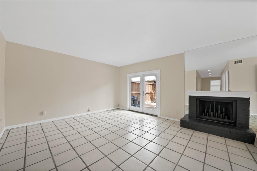 Spacious room with large ceramic tile flooring, a prominent black brick fireplace with a white mantel, and mirrored wall accents