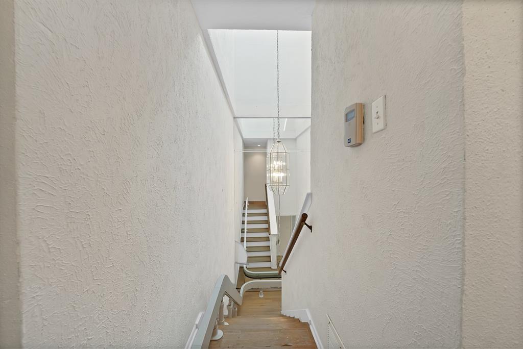 Stairwell featuring wood-finish flooring, white risers, and a contemporary chandelier