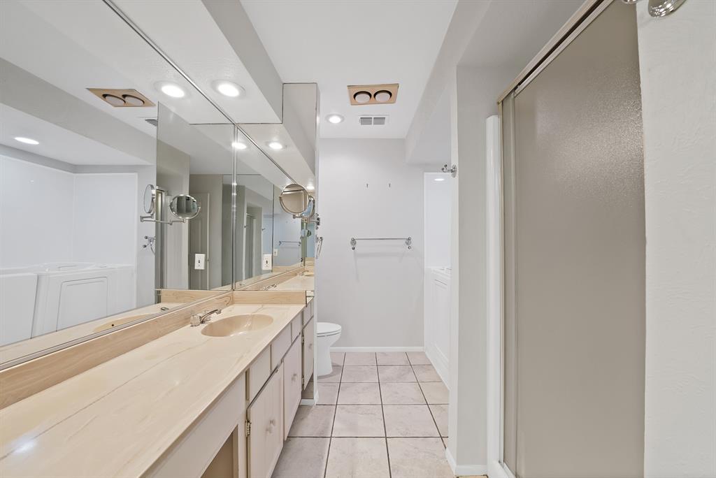 Bathroom featuring a dual vanity with light-toned countertops, integrated sinks, and extensive mirror coverage