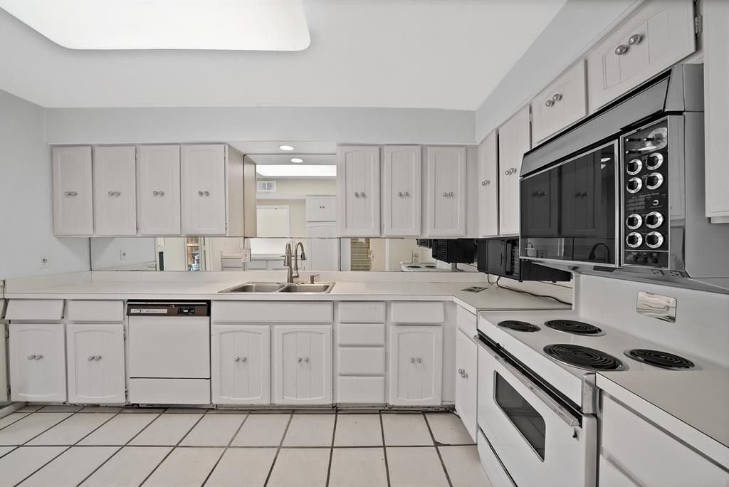 Kitchen featuring white cabinetry with silver hardware, a white solid surface countertop, an undermount double basin sink with a gooseneck faucet, a built-in dishwasher, and an electric range with an overhead microwave