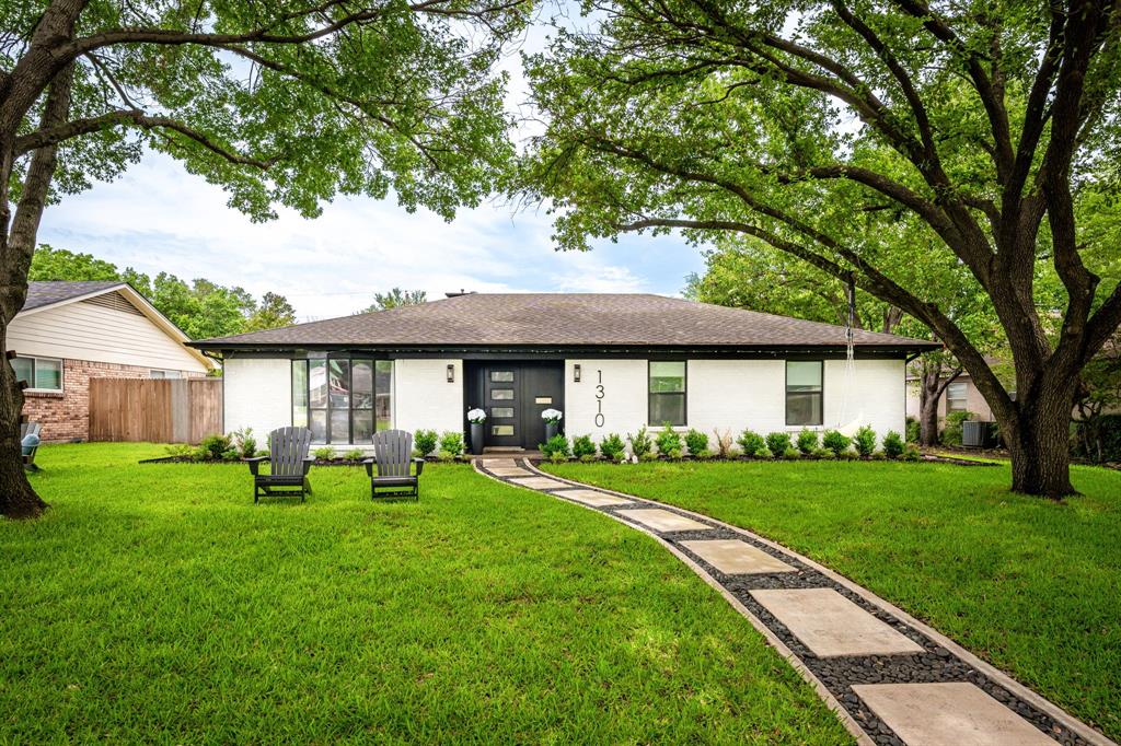 Single-story residence featuring a white exterior, dark trim, and a prominent black front door with horizontal glass panels Single-story residence featuring a white exterior, dark trim, and a prominent black front door with horizontal glass panels