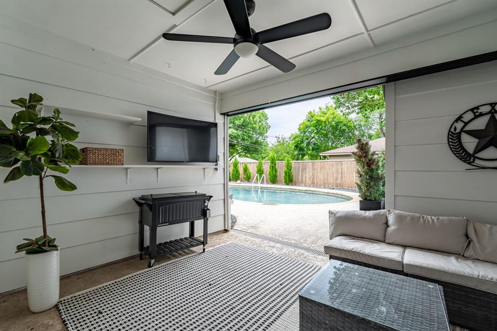 Covered patio with a mounted television, ceiling fan, and direct access to the outdoor swimming pool