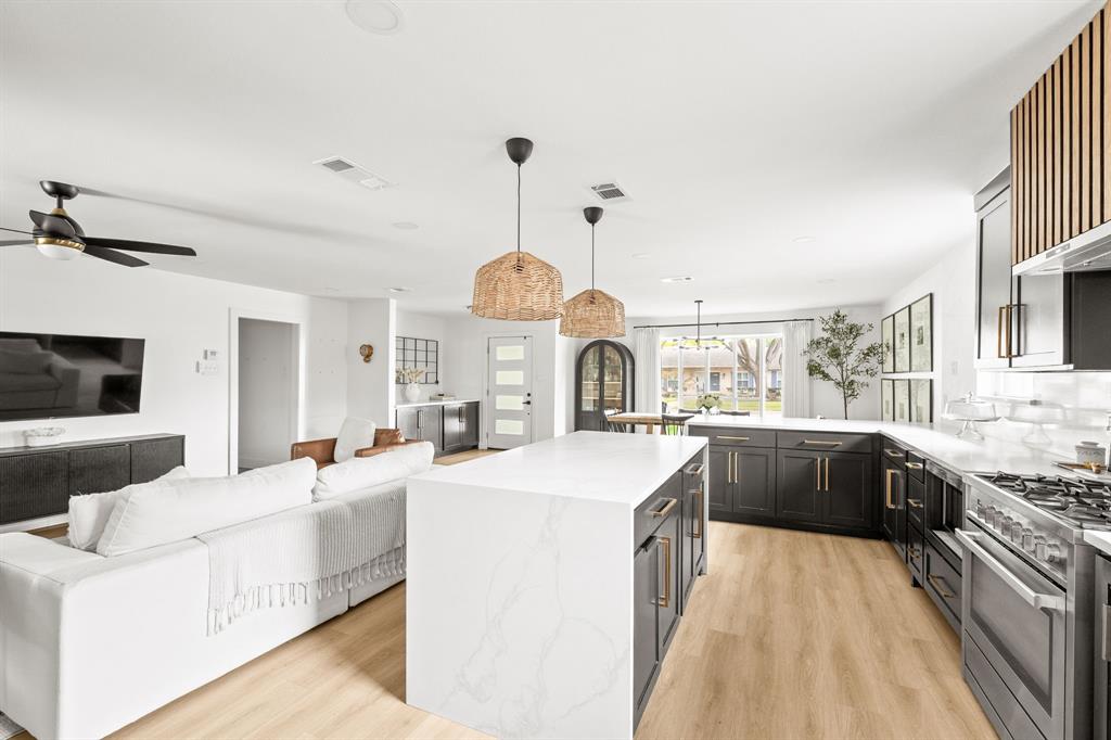 Open-concept living space featuring a gourmet kitchen with a central island, dark cabinetry, and light countertops Open-concept living space featuring a gourmet kitchen with a central island, dark cabinetry, and light countertops