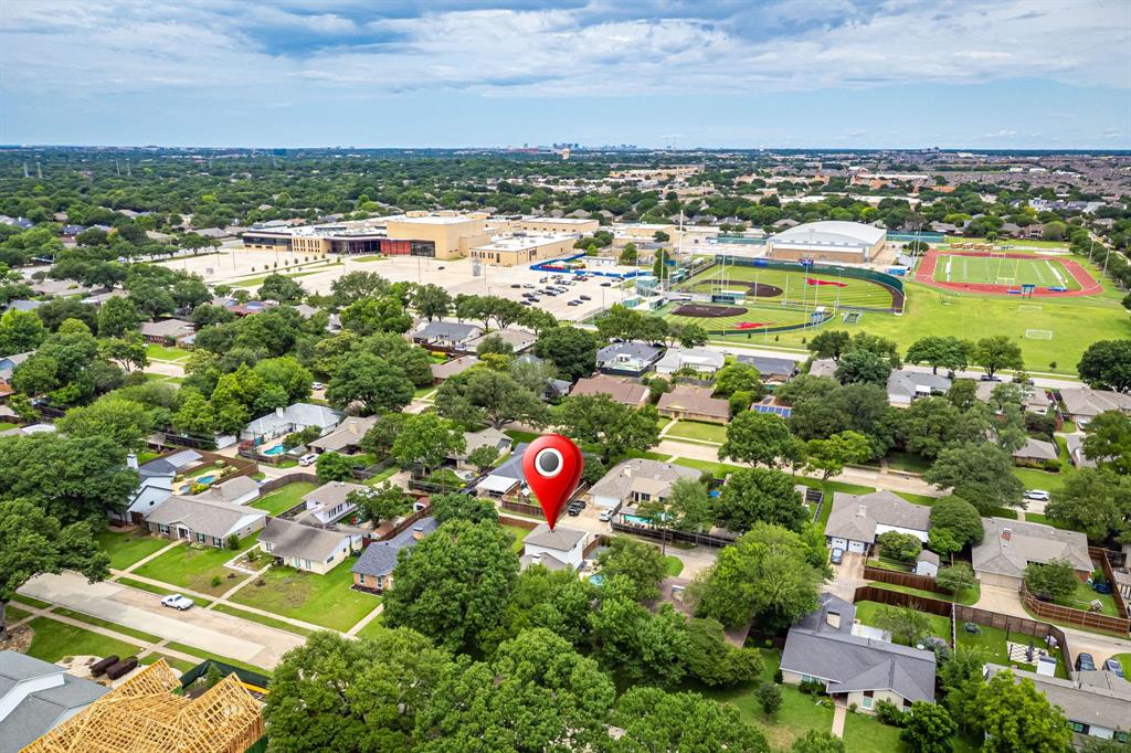 Residential neighborhood with mature trees and a nearby sports complex featuring a baseball field and track