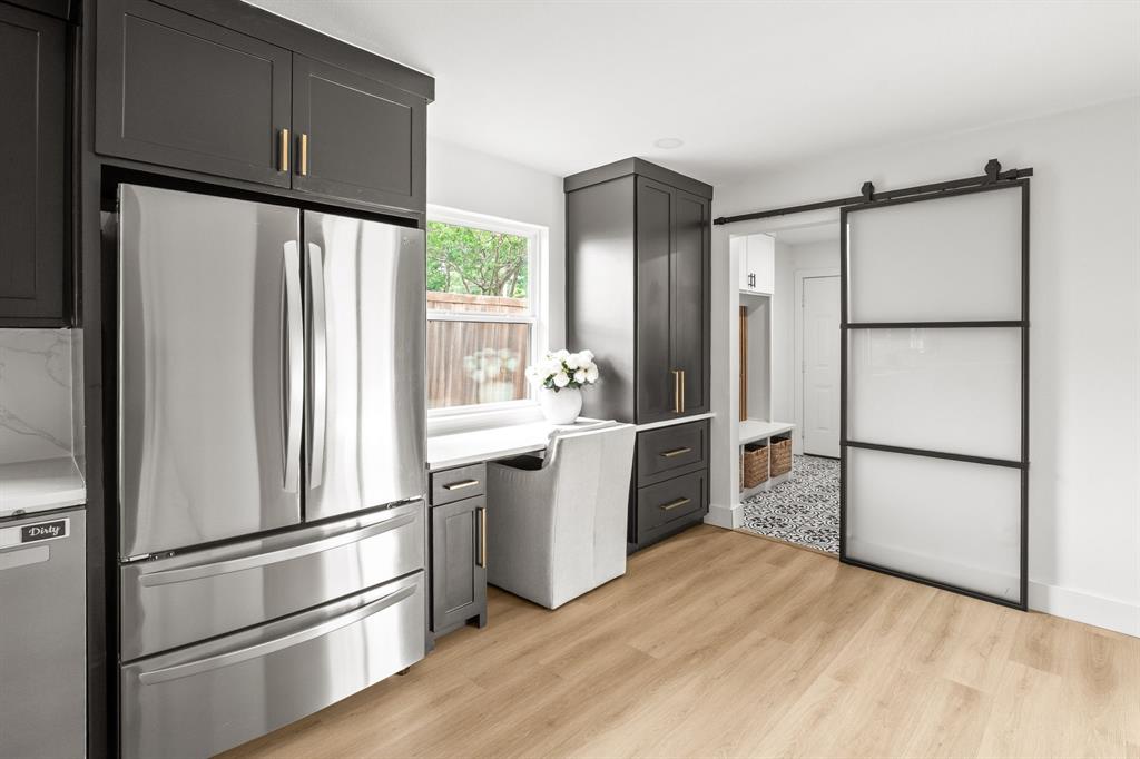 Sleek stainless steel refrigerator integrated into dark cabinetry with brass hardware