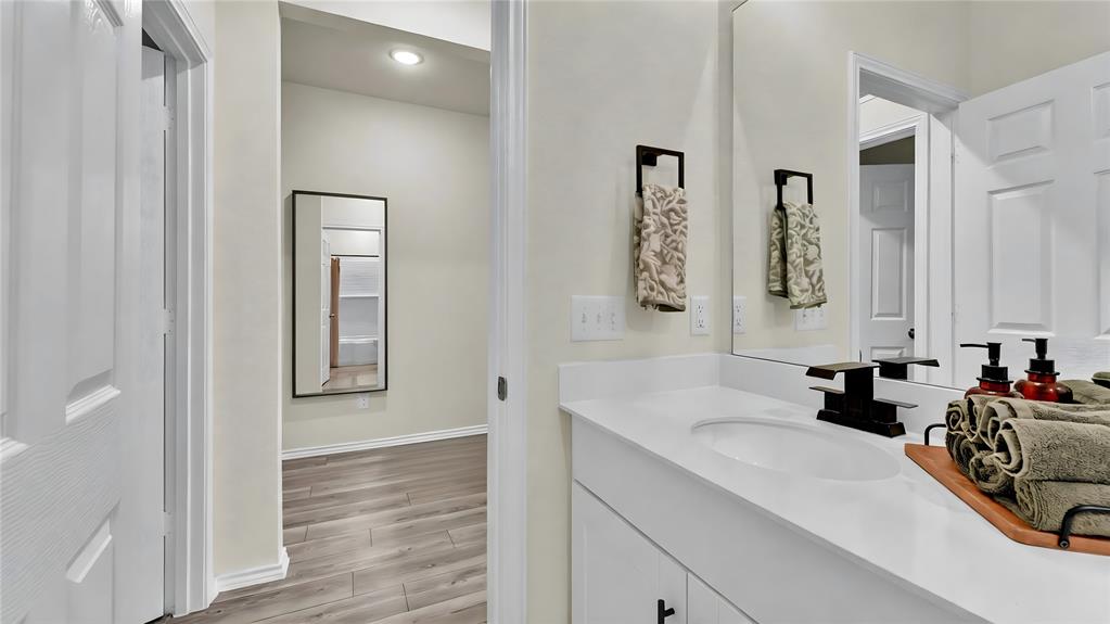 Bathroom vanity featuring an integrated sink, white countertop, and dark-finish faucet