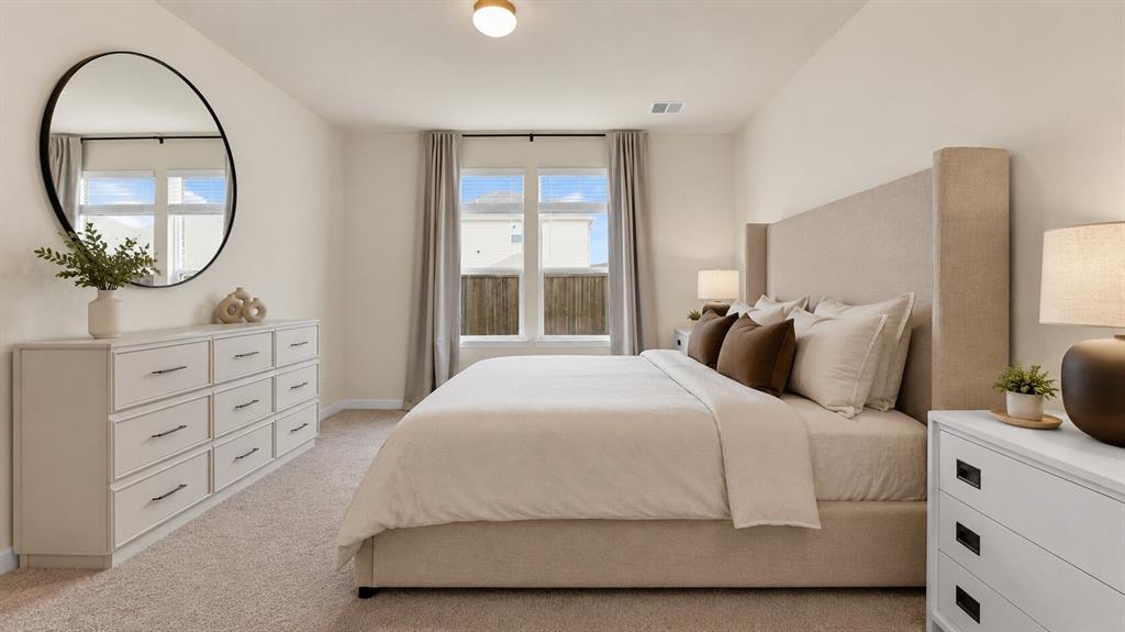 Spacious bedroom featuring light-colored walls, carpet flooring, a ceiling-mounted light fixture, and large windows with blinds and curtains