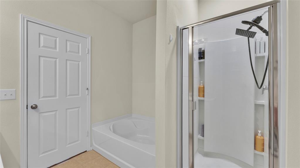 Bathroom featuring a soaking tub, a multi-function shower with a glass enclosure, built-in shower shelving, and a six-panel interior door