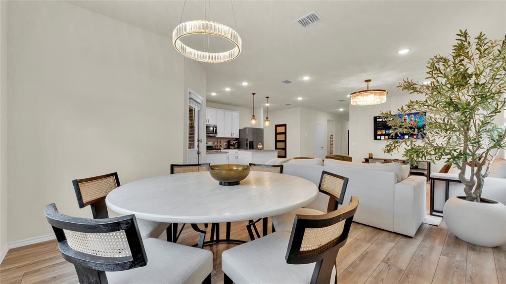 Open-concept living area featuring wood-finish flooring, recessed lighting, and a modern chandelier