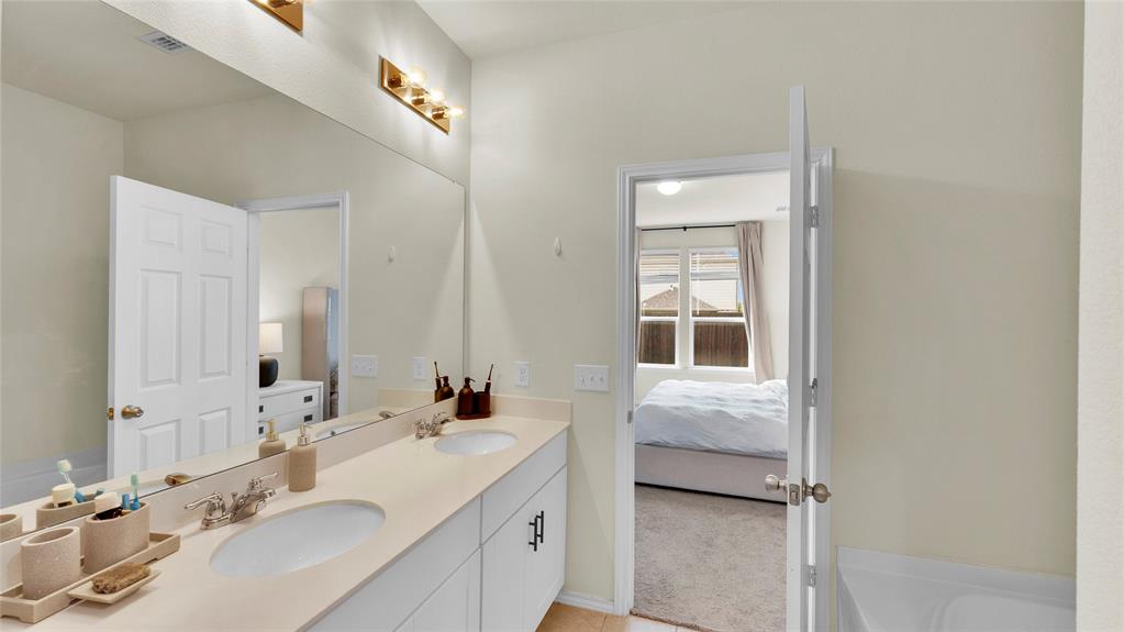 Bathroom featuring a dual vanity with undermount sinks, a large mirror, and a three-light fixture