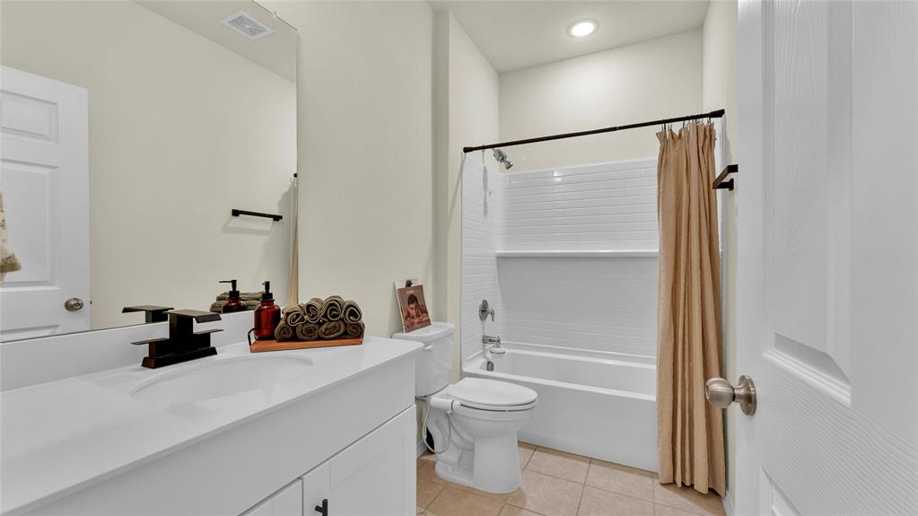 Bathroom featuring a white vanity with integrated sink, a rectangular mirror, a shower-over-tub combination with white subway tile surround, and neutral tile flooring