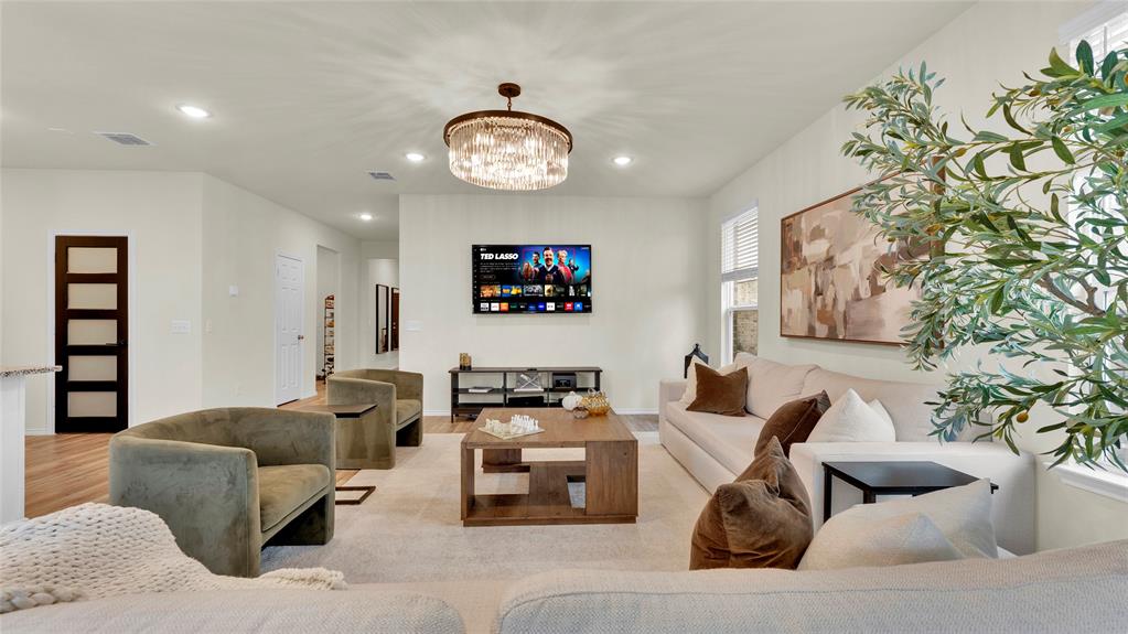 Expansive living area featuring recessed lighting, a contemporary chandelier, wood-finish flooring, and white walls