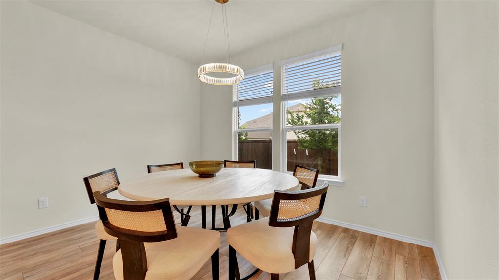 Dining area featuring light wood-finish flooring, neutral wall tones, and a modern circular chandelier