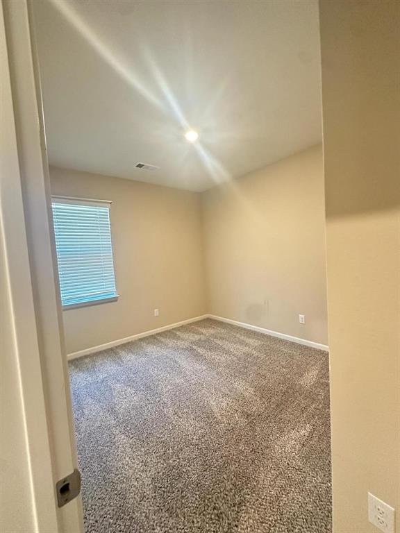 Neutral-toned carpeting complements light wall paint in this room featuring a window with horizontal blinds and a ceiling-mounted light fixture