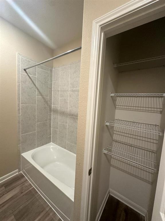 Bathroom featuring a white bathtub with light gray rectangular tile surround and a chrome shower rod