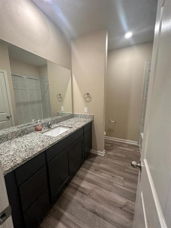 Spacious bathroom featuring a long vanity with a light granite countertop, dark cabinetry, and a large mirror