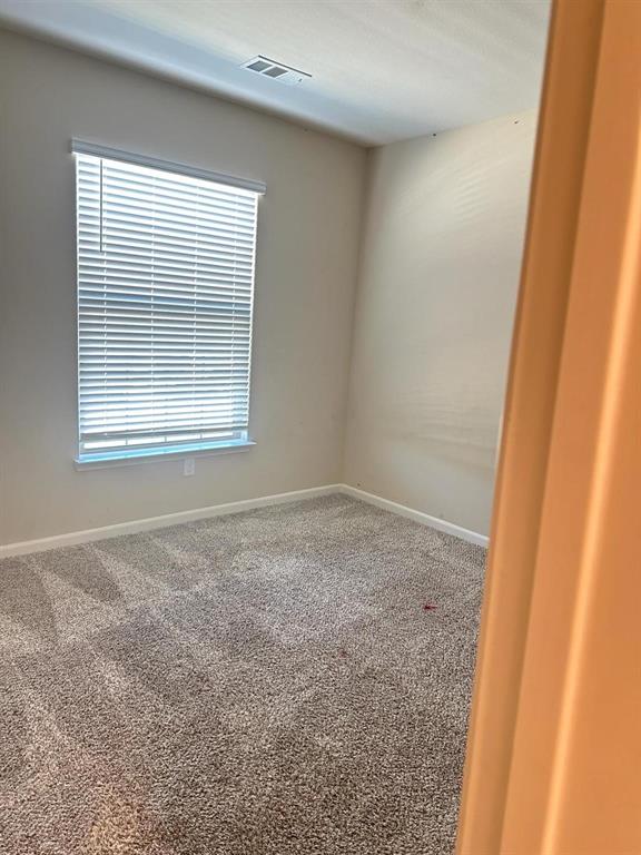 Carpeted room featuring a white window blind, light-colored walls, white trim, and a ceiling vent