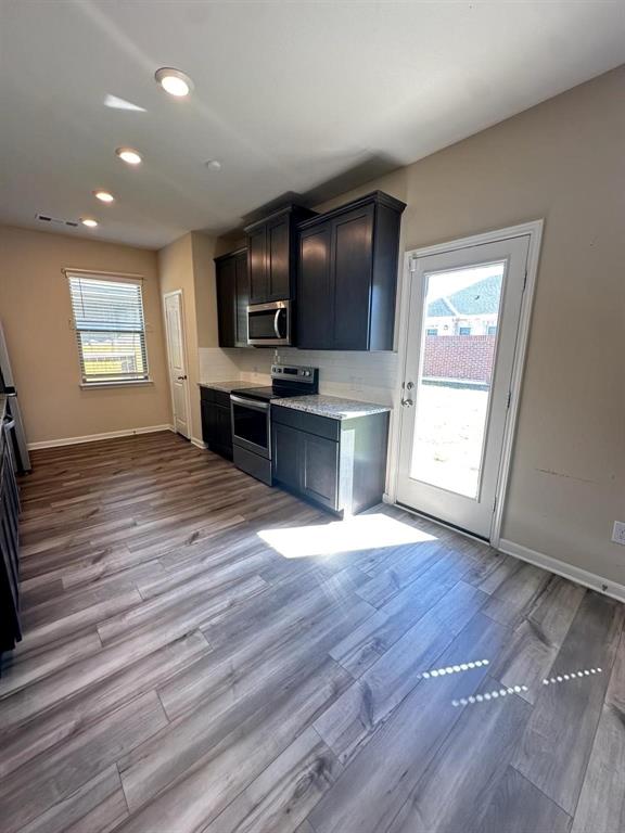 Modern kitchen featuring wood-finish flooring, dark cabinetry, light-toned countertops, and recessed lighting