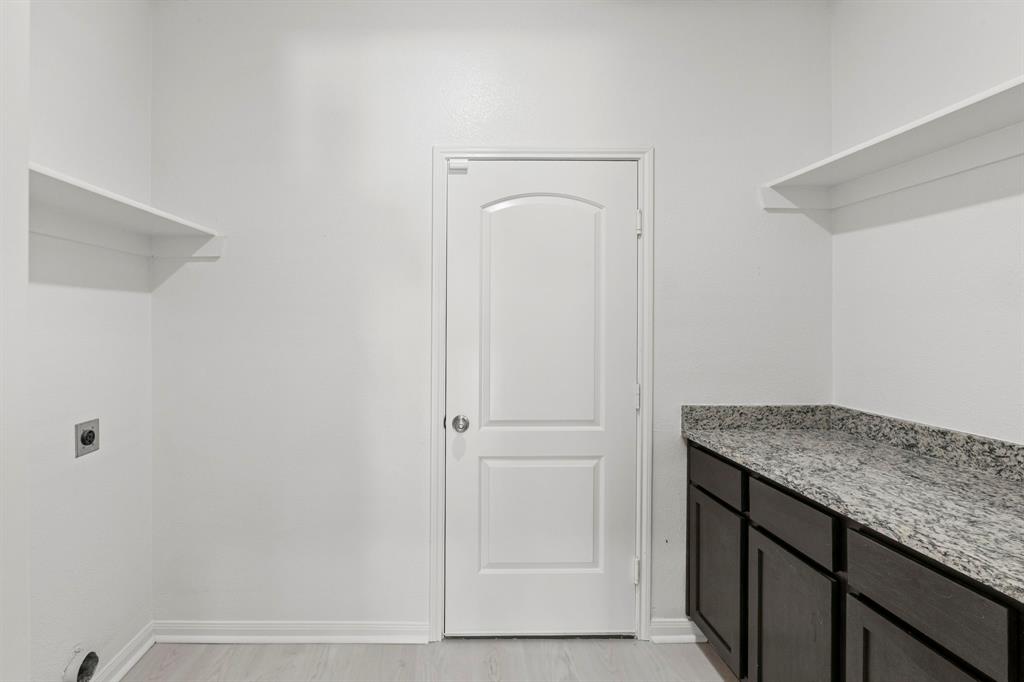 Utility space featuring dark wood-finish cabinetry, a speckled countertop, and two built-in storage shelves