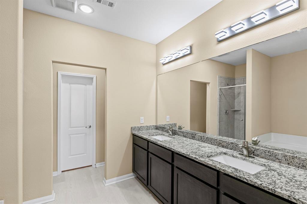 Bathroom featuring a double vanity with granite-finish countertops, dark wood-finish cabinetry, and undermount sinks