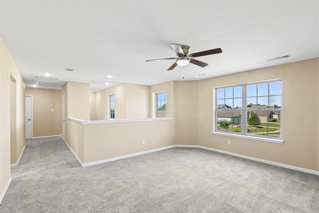 Spacious loft area featuring light gray carpet flooring and neutral wall tones