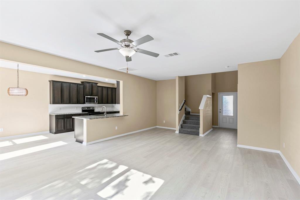 Open-concept living area featuring light wood-finish flooring, a contemporary ceiling fan, and recessed lighting Open-concept living area featuring light wood-finish flooring, a contemporary ceiling fan, and recessed lighting