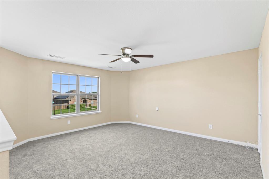 Carpeted interior space featuring neutral wall tones, a ceiling fan with integrated lighting, and a multi-pane window