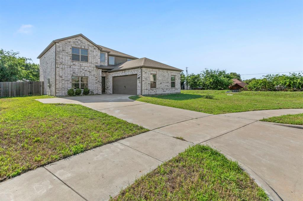 Two-story brick exterior featuring a multi-pane window design, an attached garage, and a concrete driveway Two-story brick exterior featuring a multi-pane window design, an attached garage, and a concrete driveway
