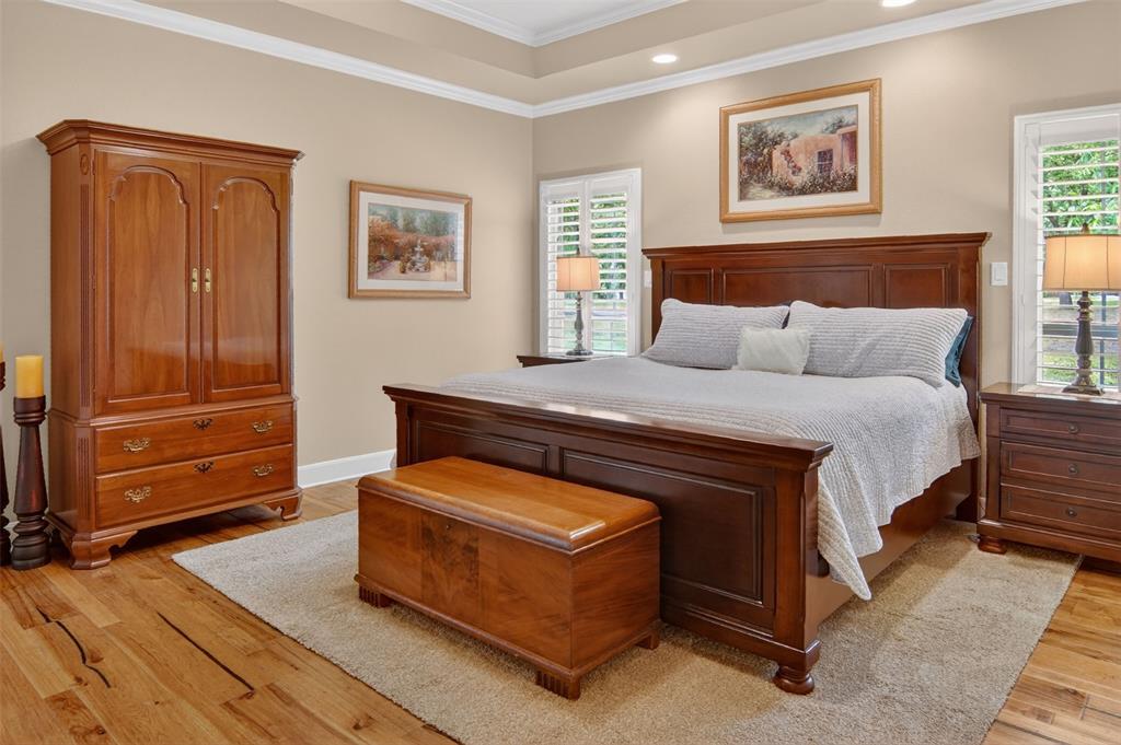 Spacious primary bedroom with wood flooring and wood shutters.